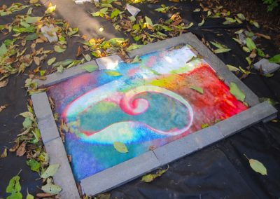 garden installation image of a twirl on earth framed around by stone bars mamta herland